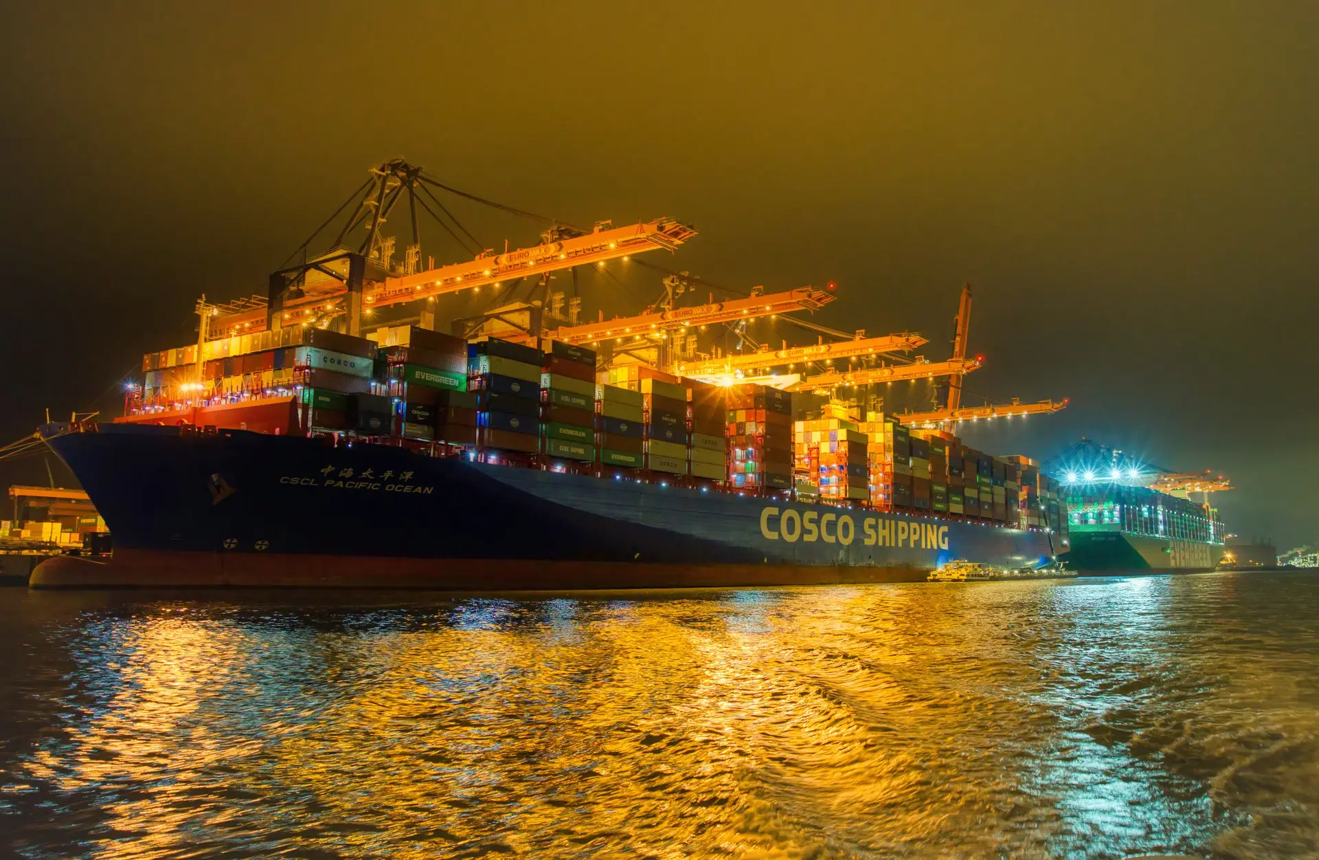 Illuminated container vessel and cranes at a port at night